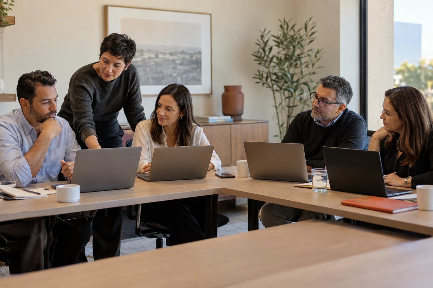Profesionales conversan alrededor de una computadora en una oficina