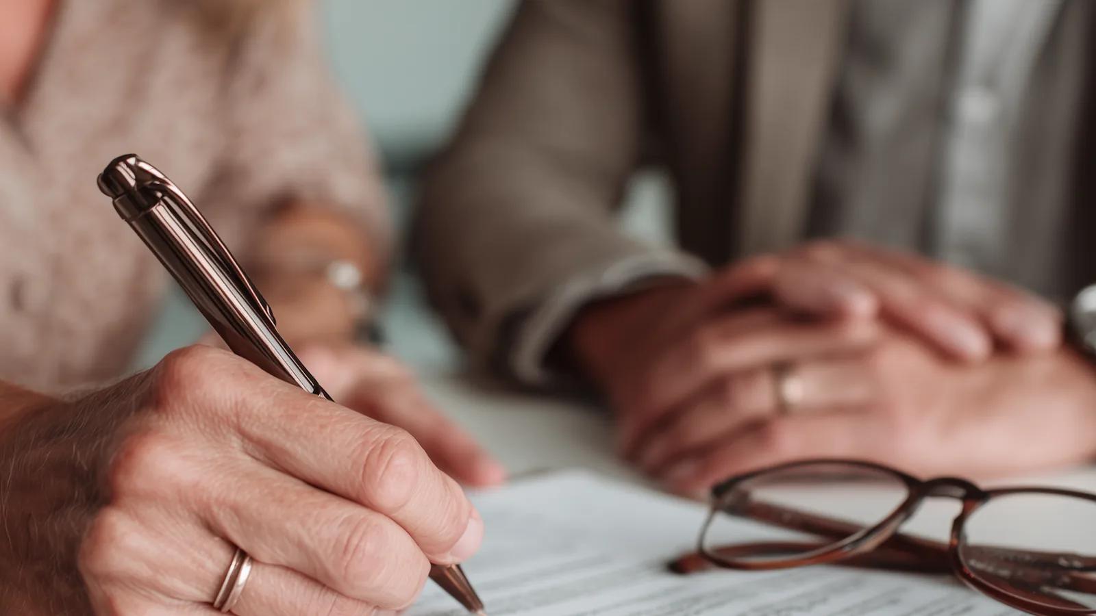 Manos firmando un contrato sobre un escritorio