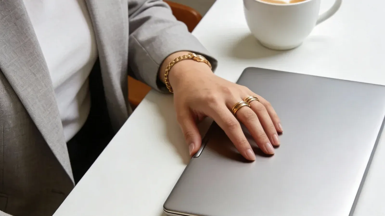 Manos protegiendo una laptop cerrada sobre un escritorio