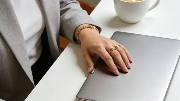 Manos protegiendo una laptop cerrada sobre un escritorio