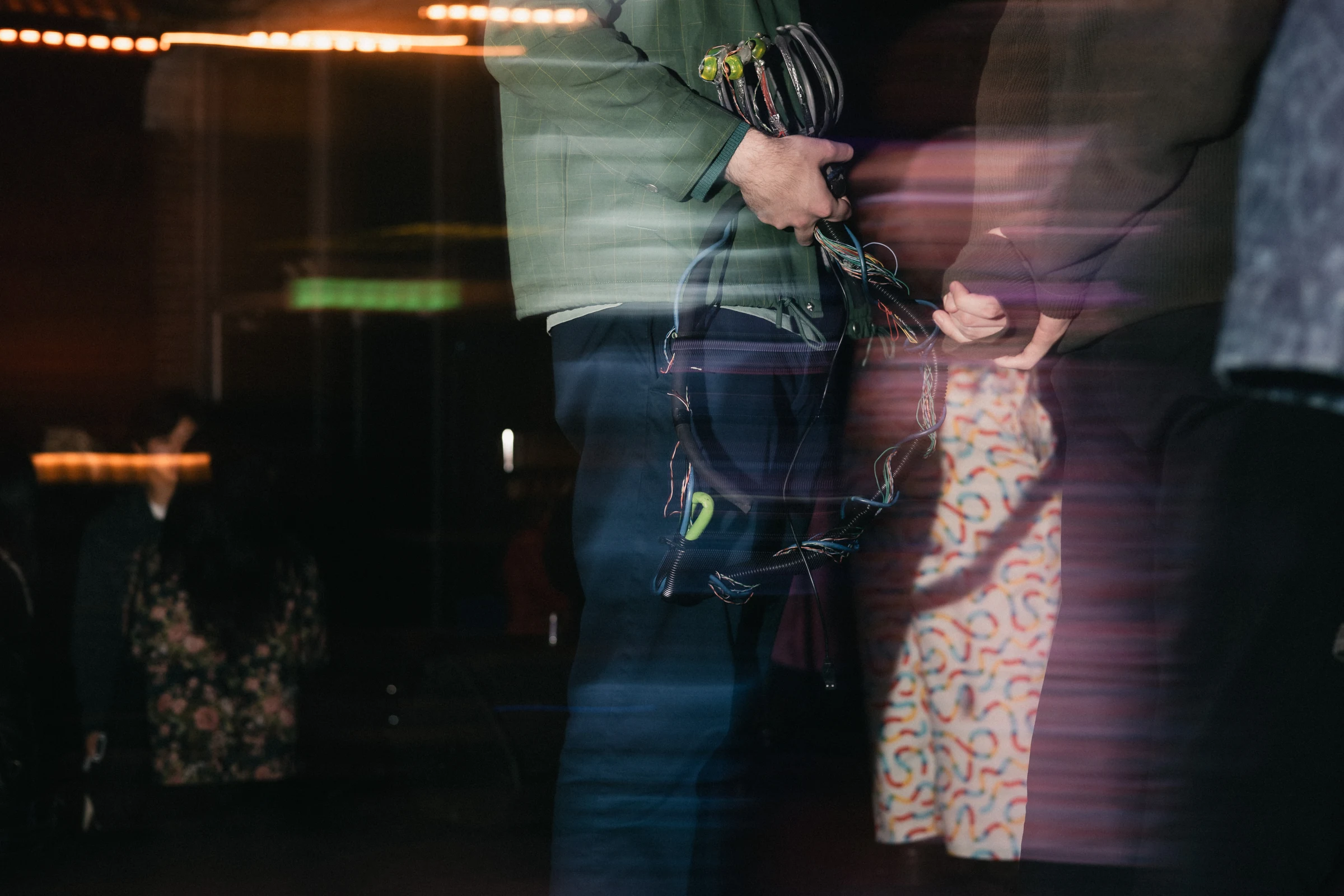 Two people stand in semi-darkness, one holding climbing gear. Blurred lighting and motion lines create a dynamic, mysterious atmosphere.