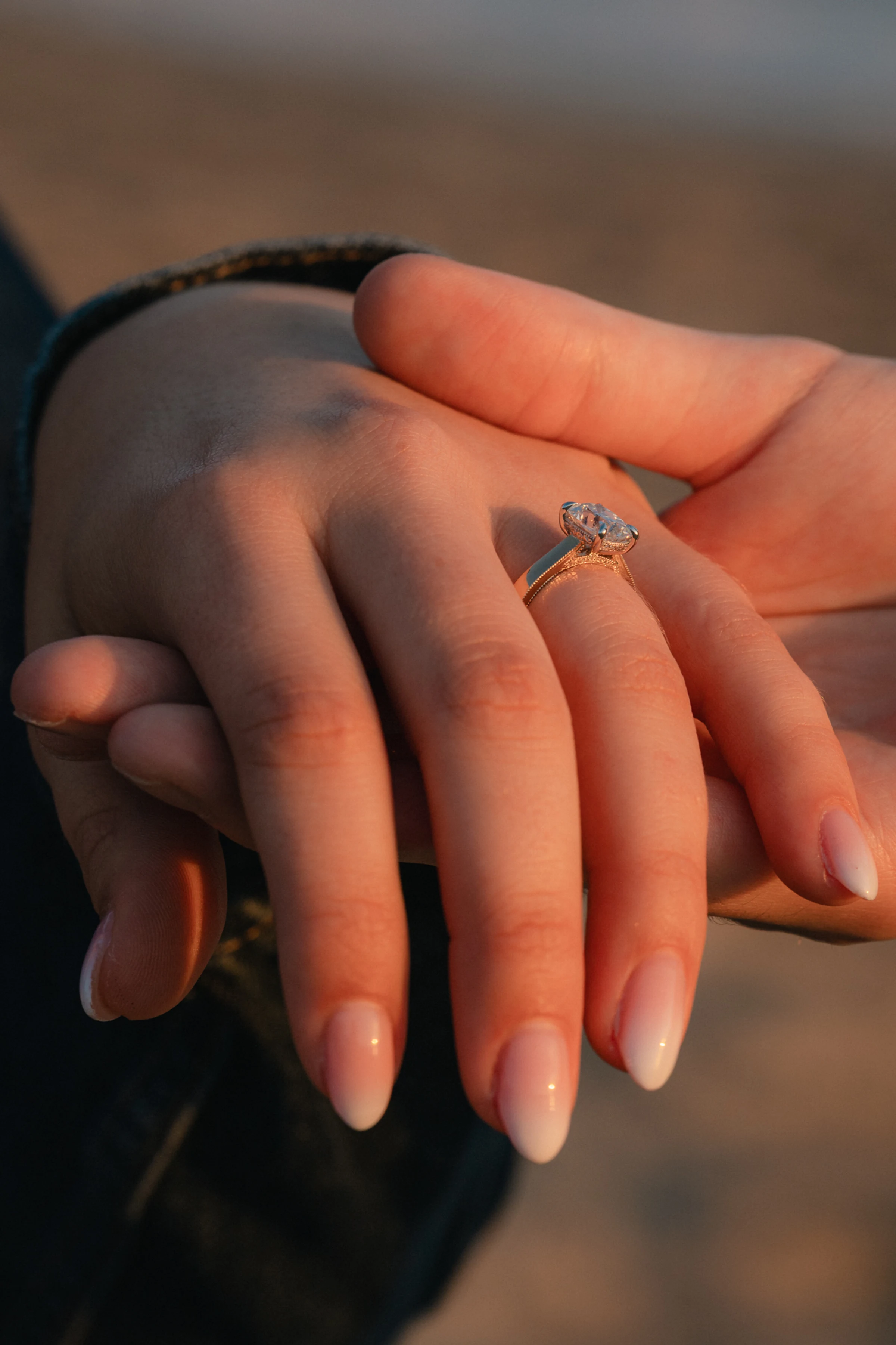 Two hands gently holding, one with a diamond engagement ring, soft lighting highlights the ring's sparkle, conveying love and commitment.