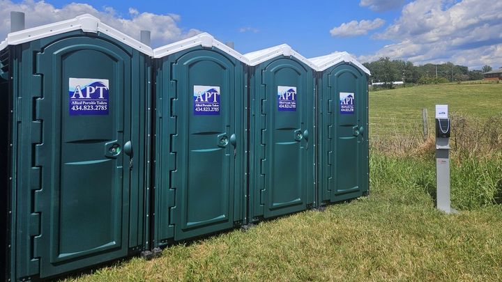 Green portable toilets lined up at an outdoor event location