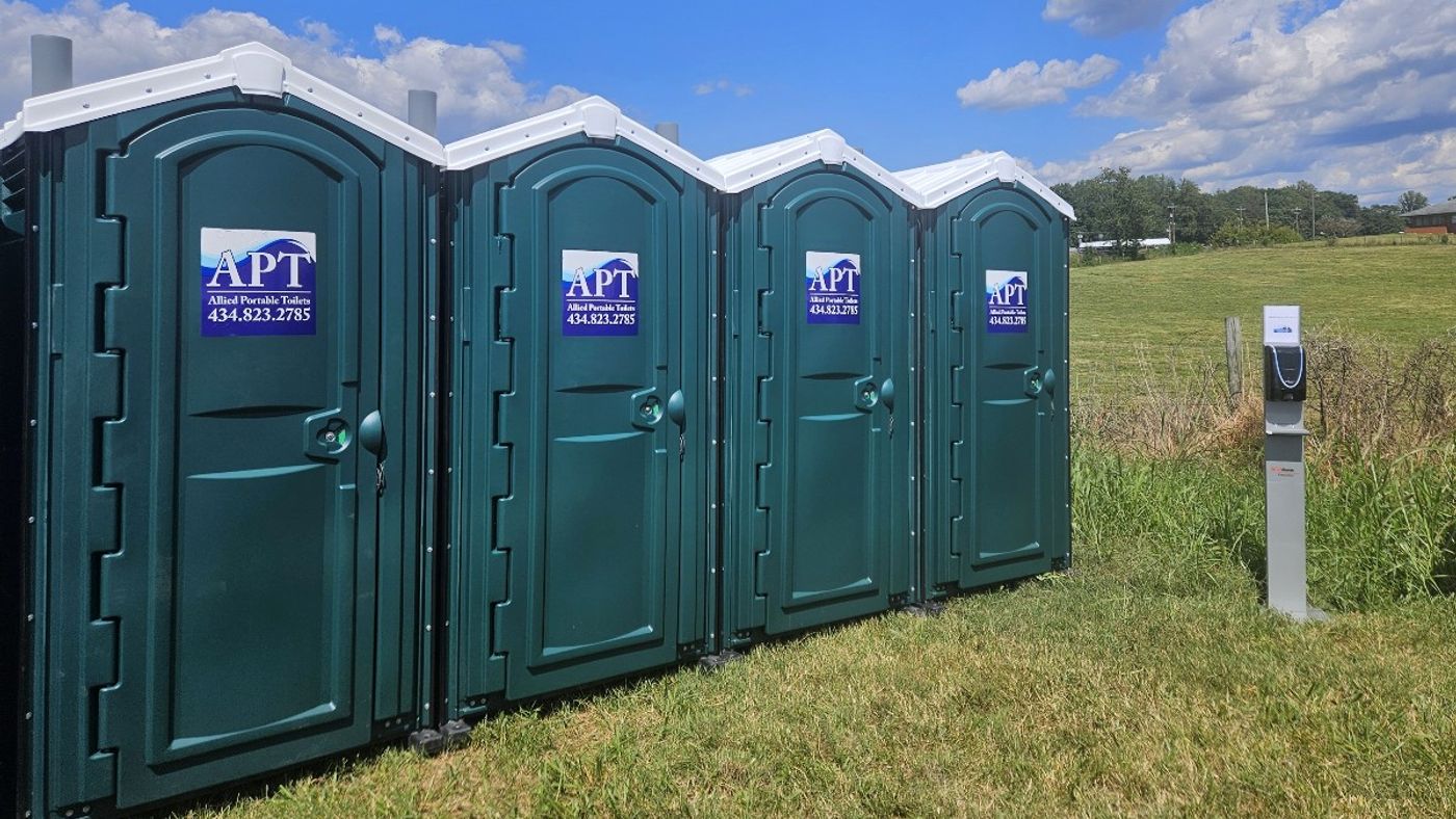 Green portable toilets lined up at an outdoor event location