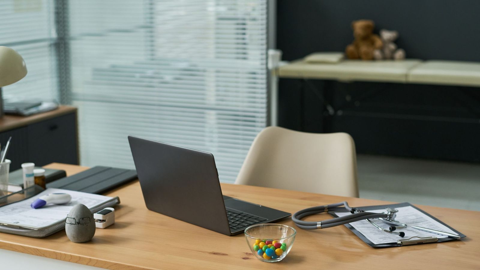 Stethoskop und geöffneter Laptop auf einem hellen Praxis-Schreibtisch