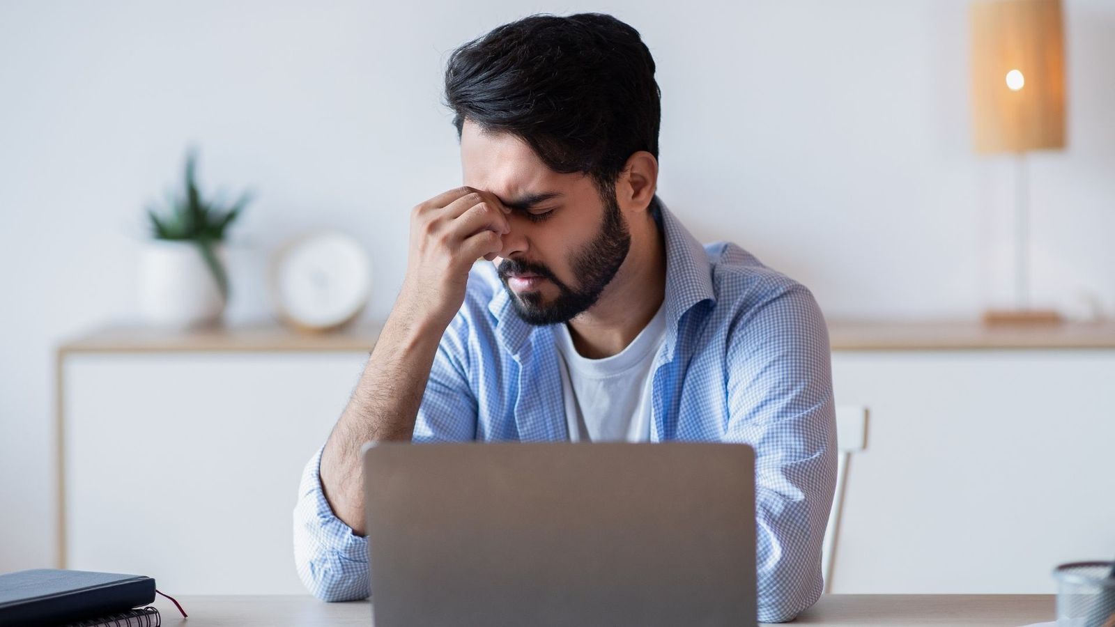 Verzweifelte Person vor einem Laptop