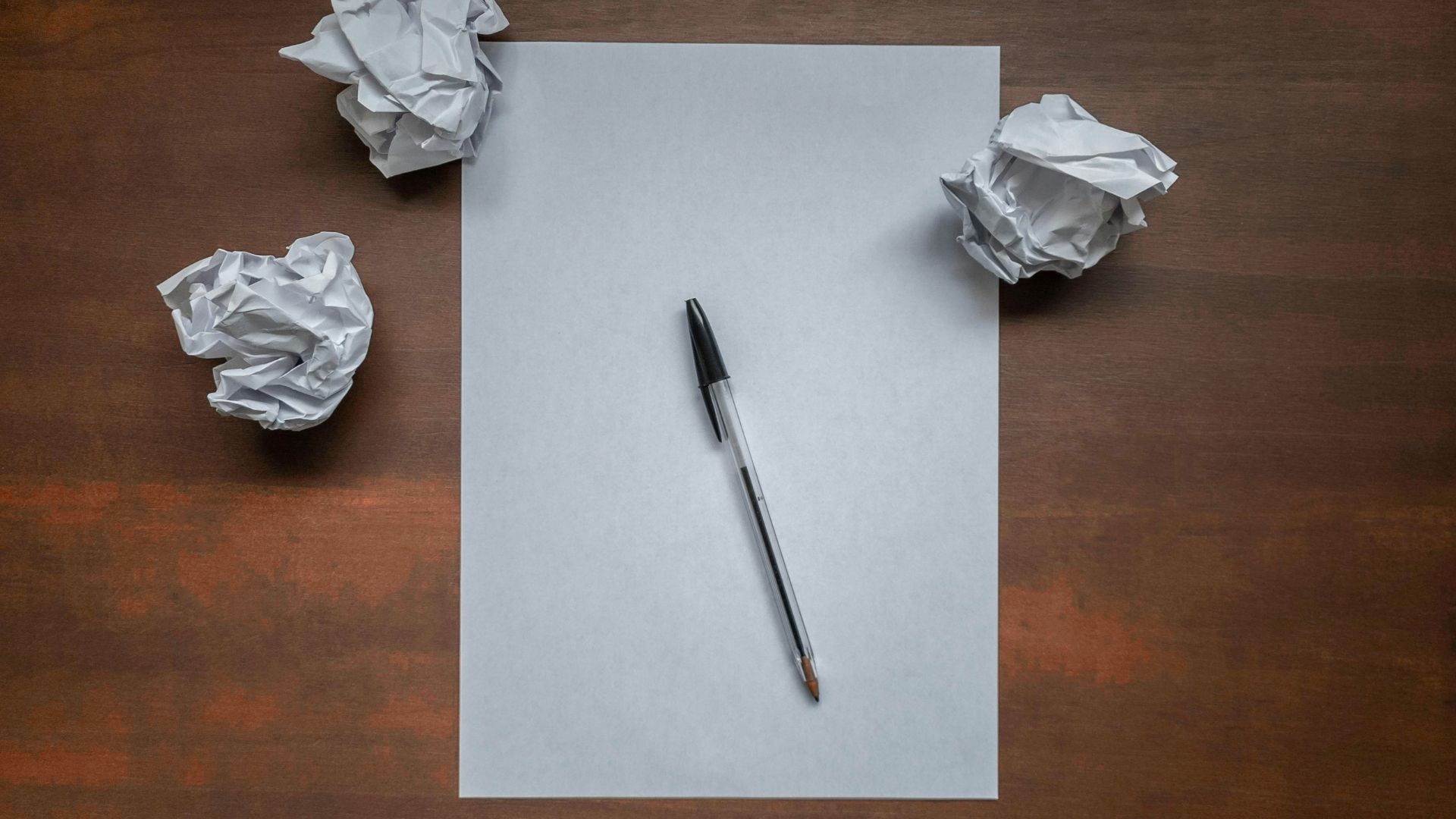 Leeres Blatt mit Kugelstift und zerknülltem Papier
