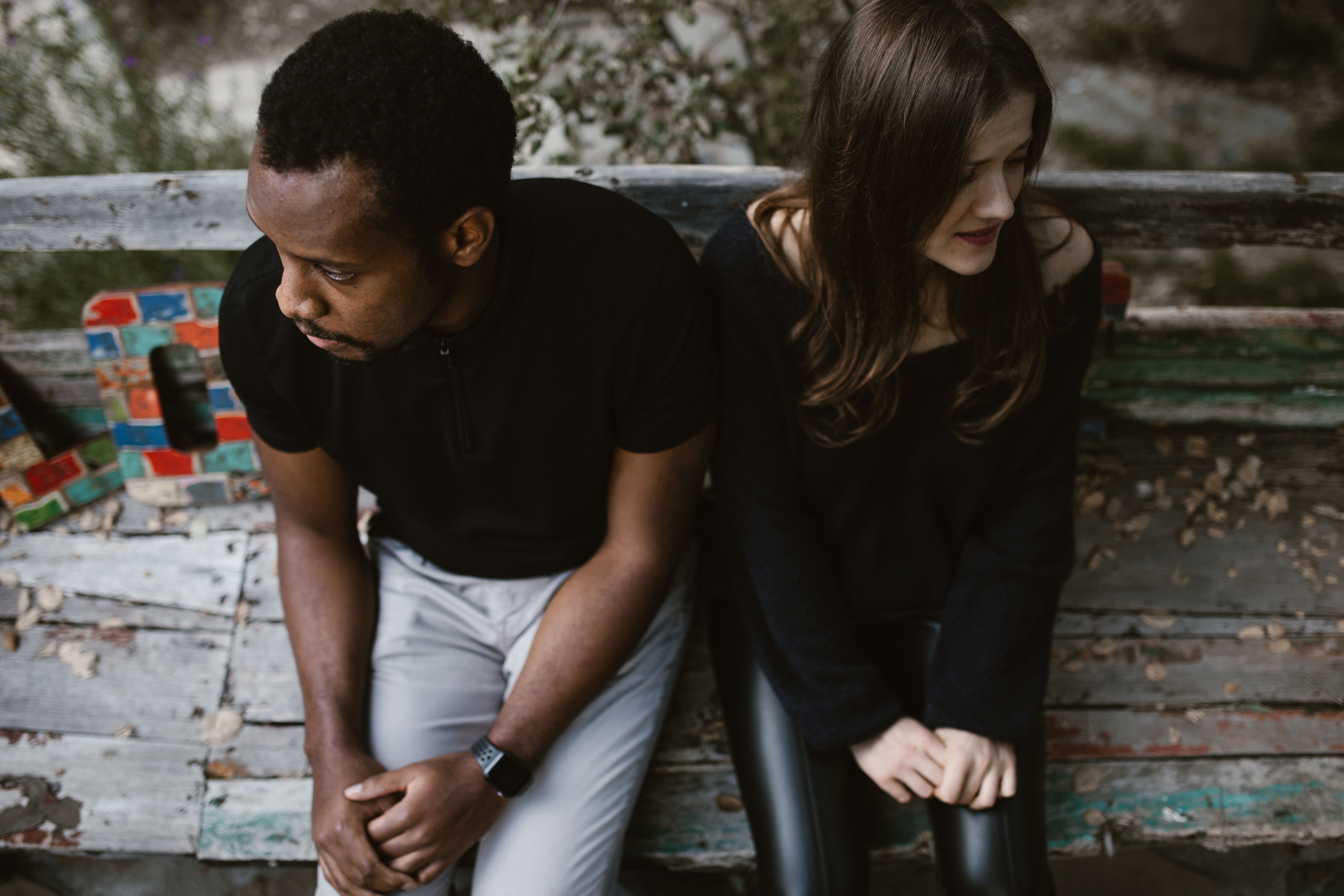 Couple sitting apart on a weathered wooden bench facing away from each other, representing the divorce process in Chicago, Illinois.