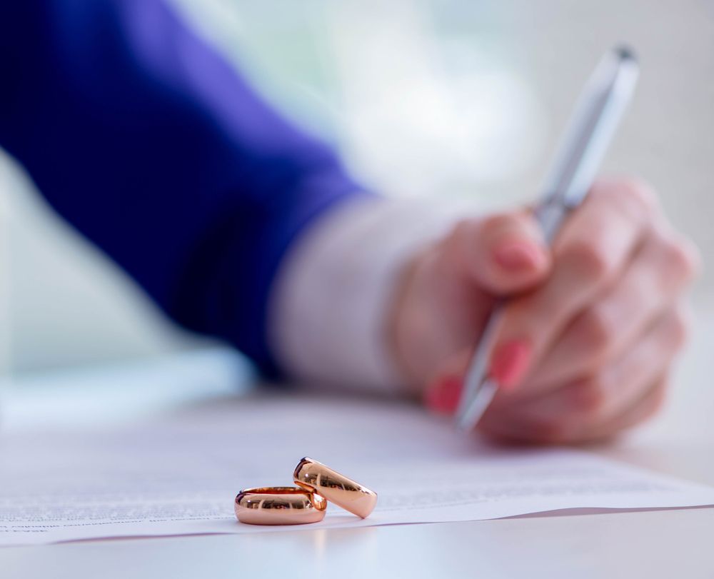 Person signing a prenuptial agreement with wedding rings on the document representing Illinois prenup enforceability in divorce cases