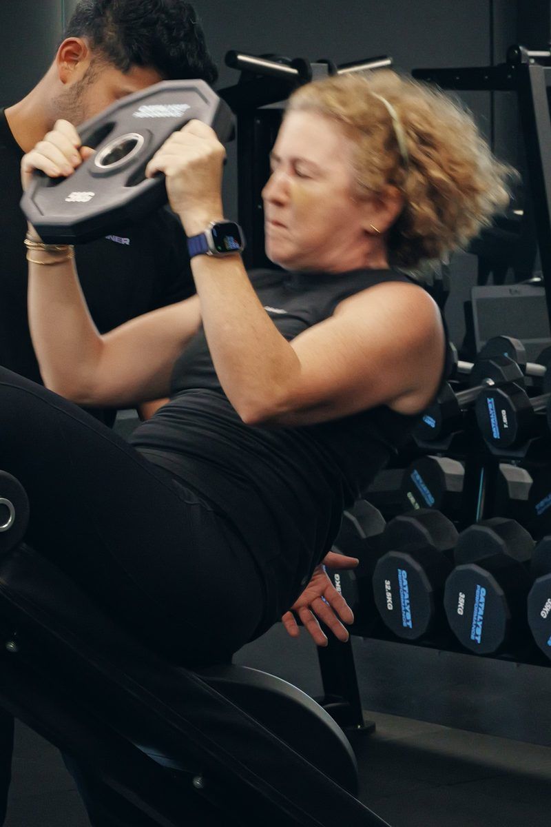 An older woman trains with added load alongside a Catalyst coach at the studio