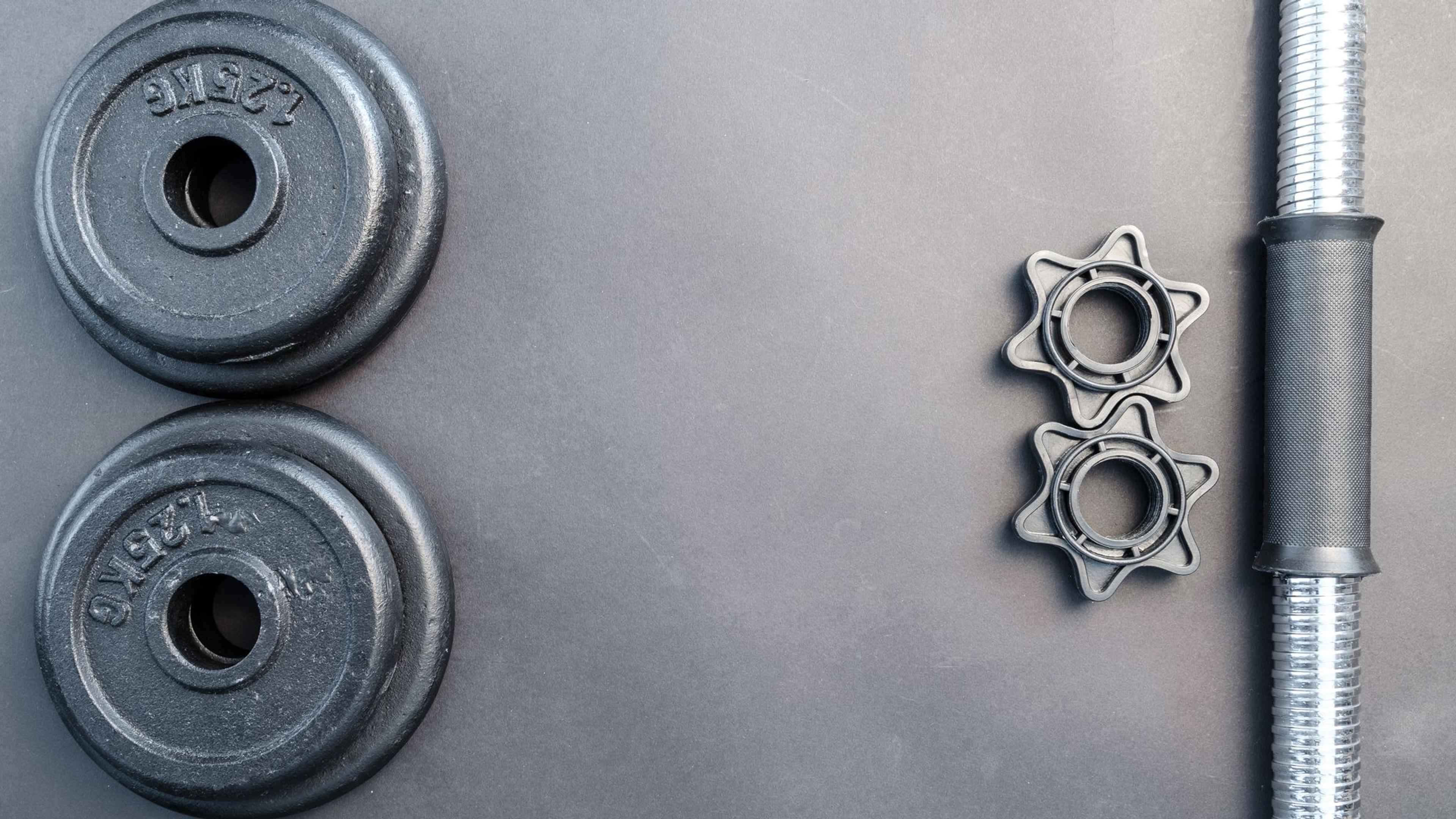 A barbell and dumbbells arranged on a neutral surface