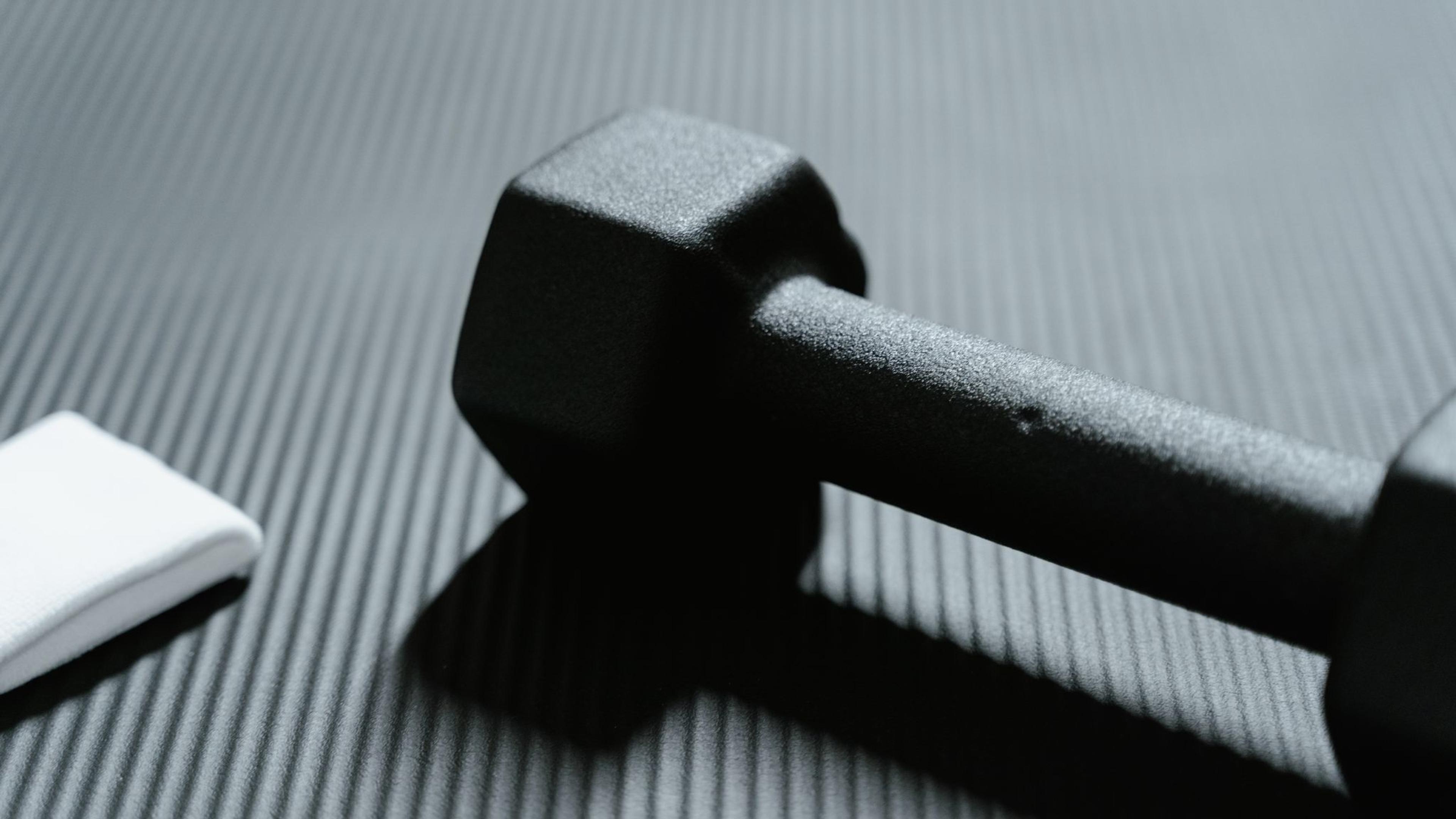 A single black dumbbell on a textured training mat