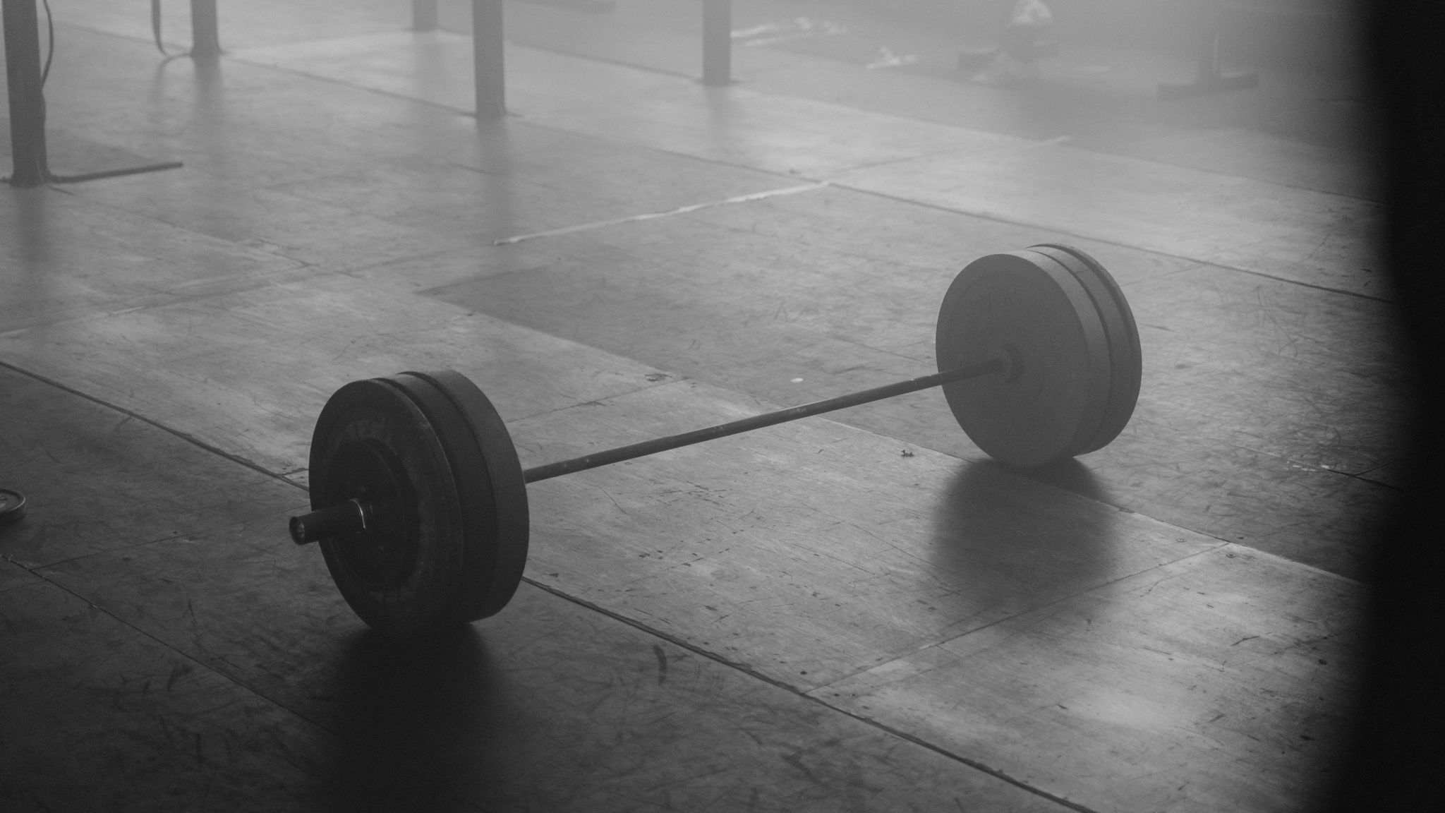 A loaded barbell resting on a studio floor in monochrome