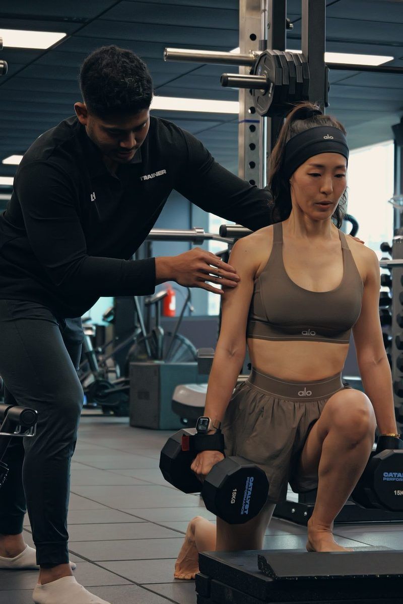 A Catalyst coach cues a woman through a weighted split squat at the studio