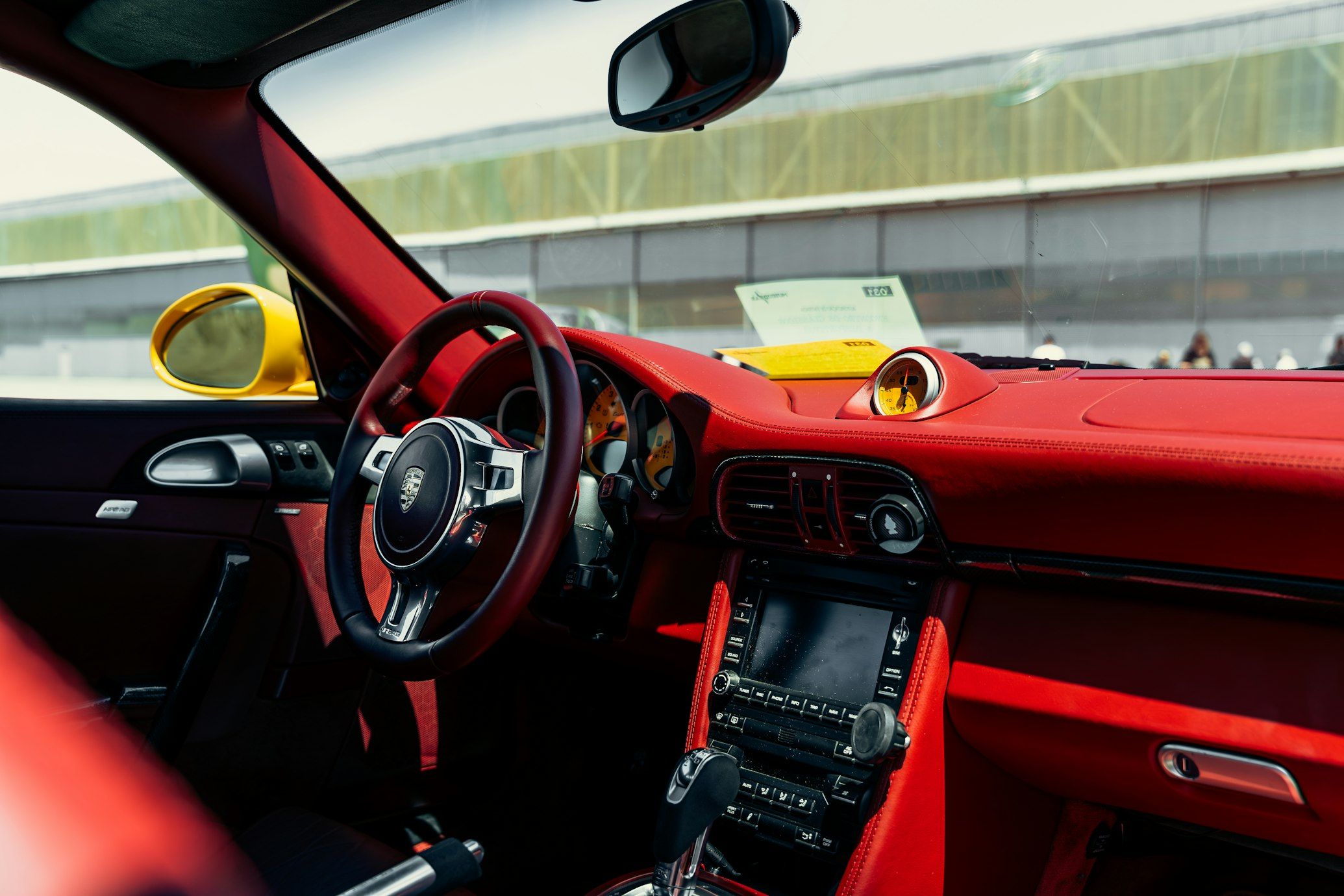 Porsche 911 cockpit with red leather dashboard, yellow instrument dials and a dashboard-mounted stopwatch.