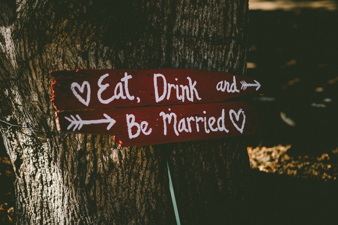 Tree Sign Wooden sign attached to a tree reads Eat Drink and Be Married with arrows.