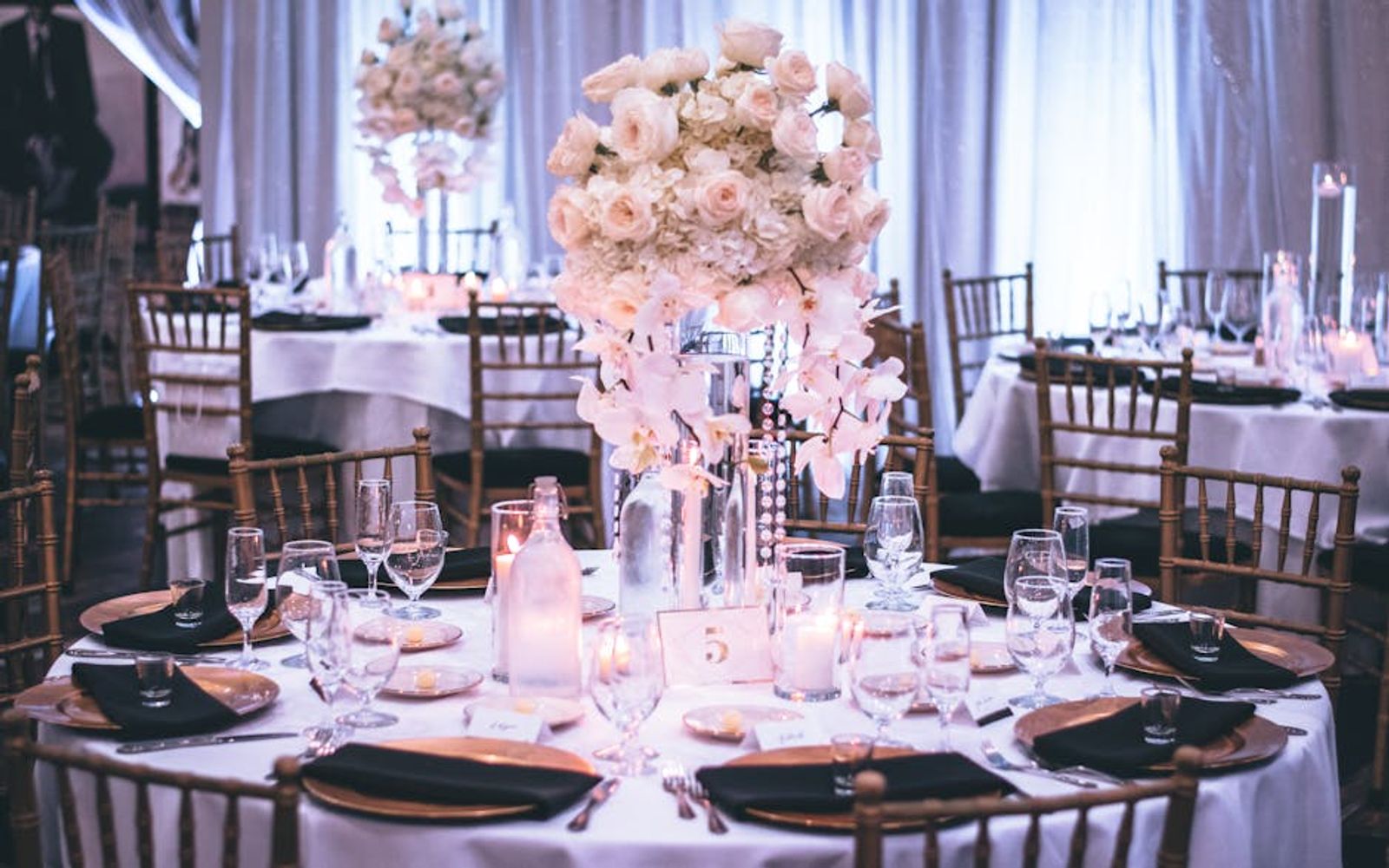 Round reception tables with pale floral centerpieces and dark wooden chairs.