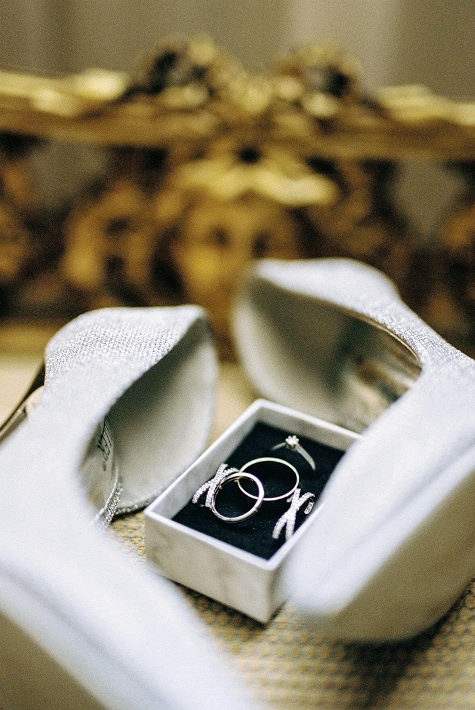 Silver shoes surround an open ring box holding two rings.