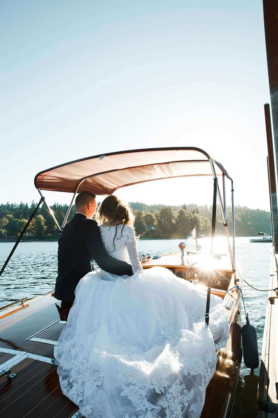 Person in a white formal dress seated at the back of a small boat.