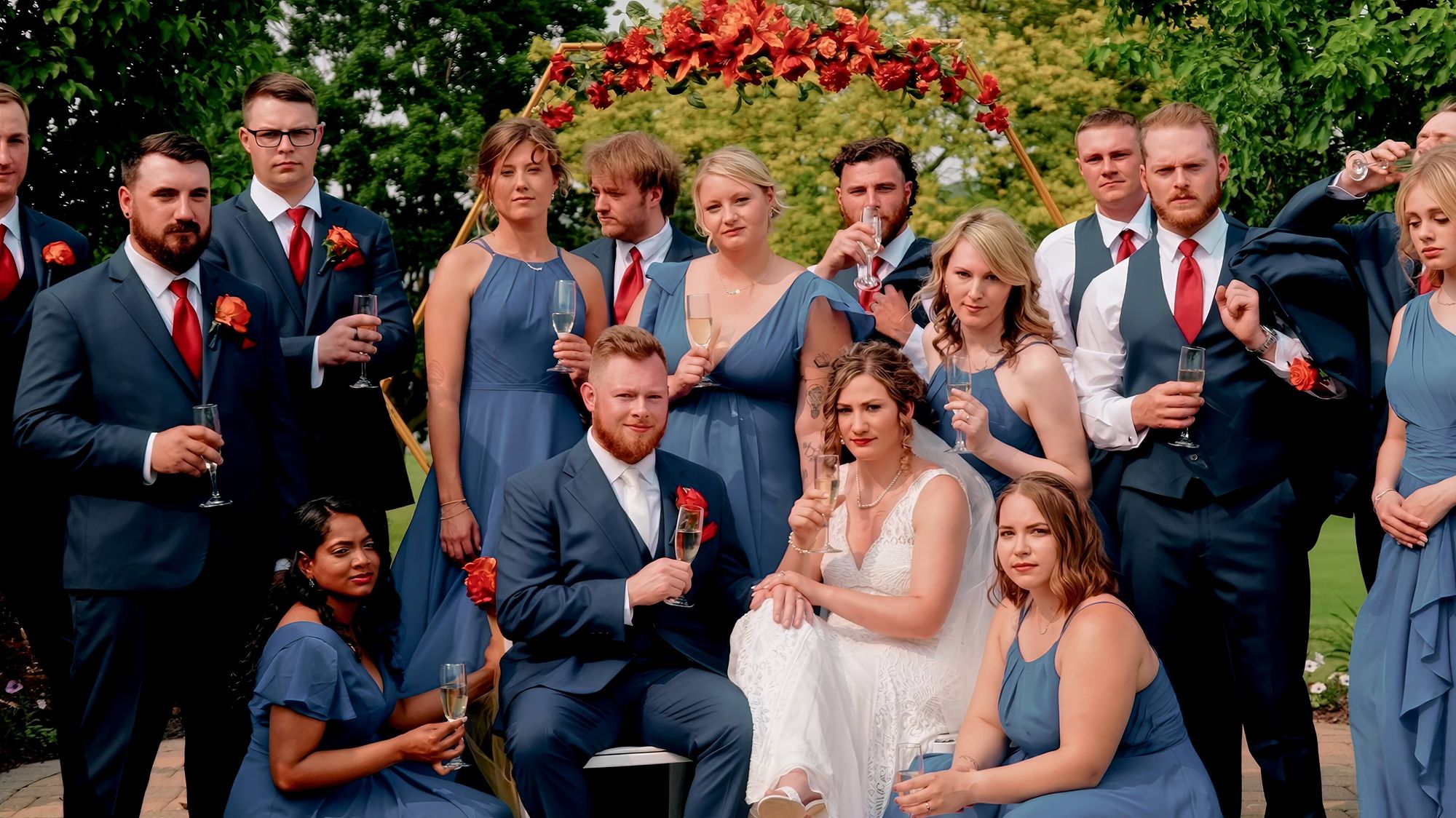 Large group in blue, black, and pink formal clothing posed outdoors.