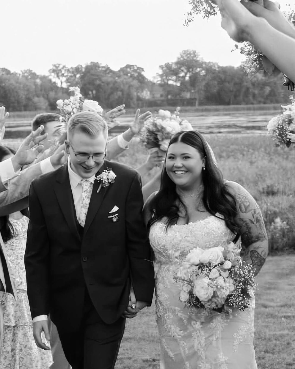 Raised Arm Walk Black-and-white image of two formally dressed people walking between raised arms.