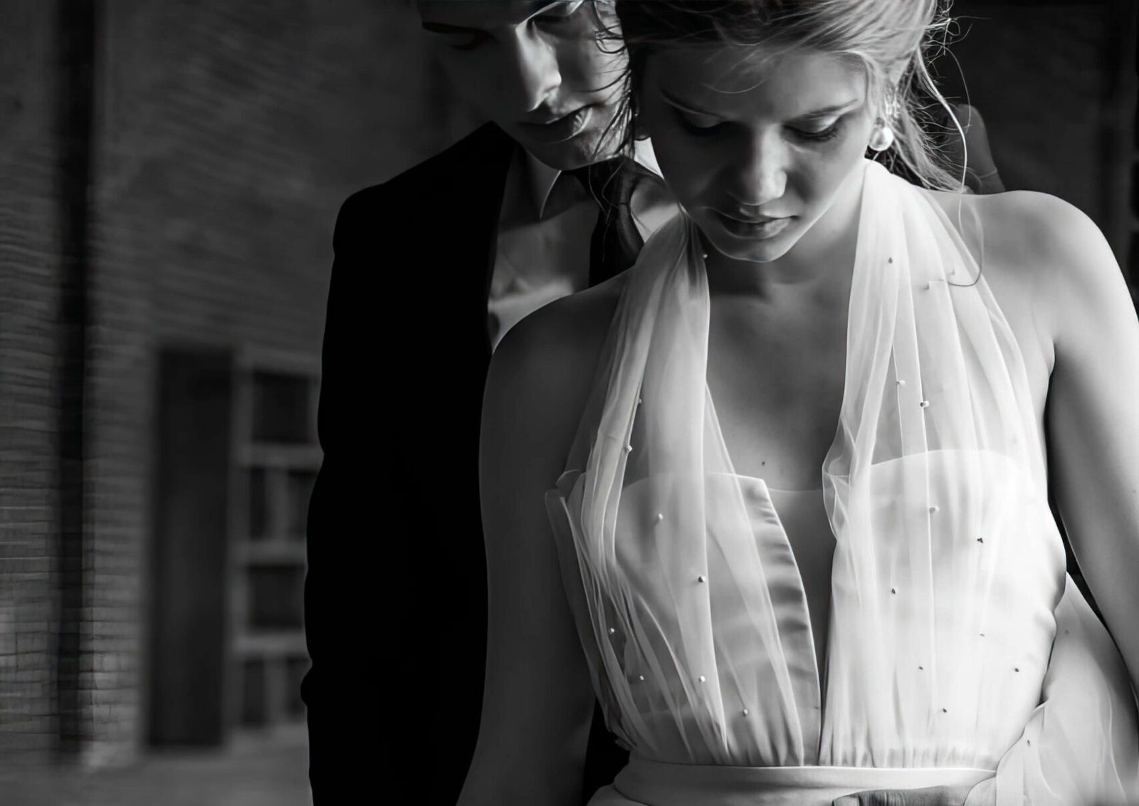Black-and-white close crop of two people in formal clothing, focused on a sleeveless beaded dress.