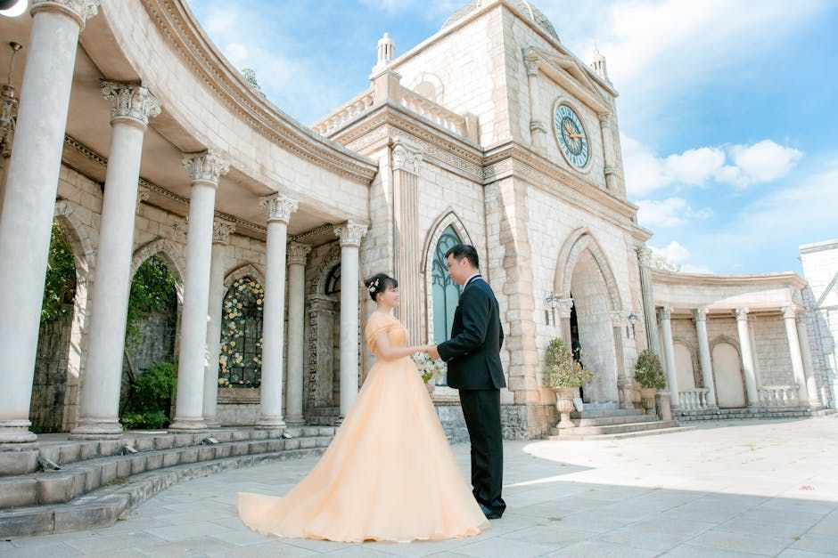 Columned Building Portrait Couple in formal clothing standing before a large white building with columns and a clock tower.