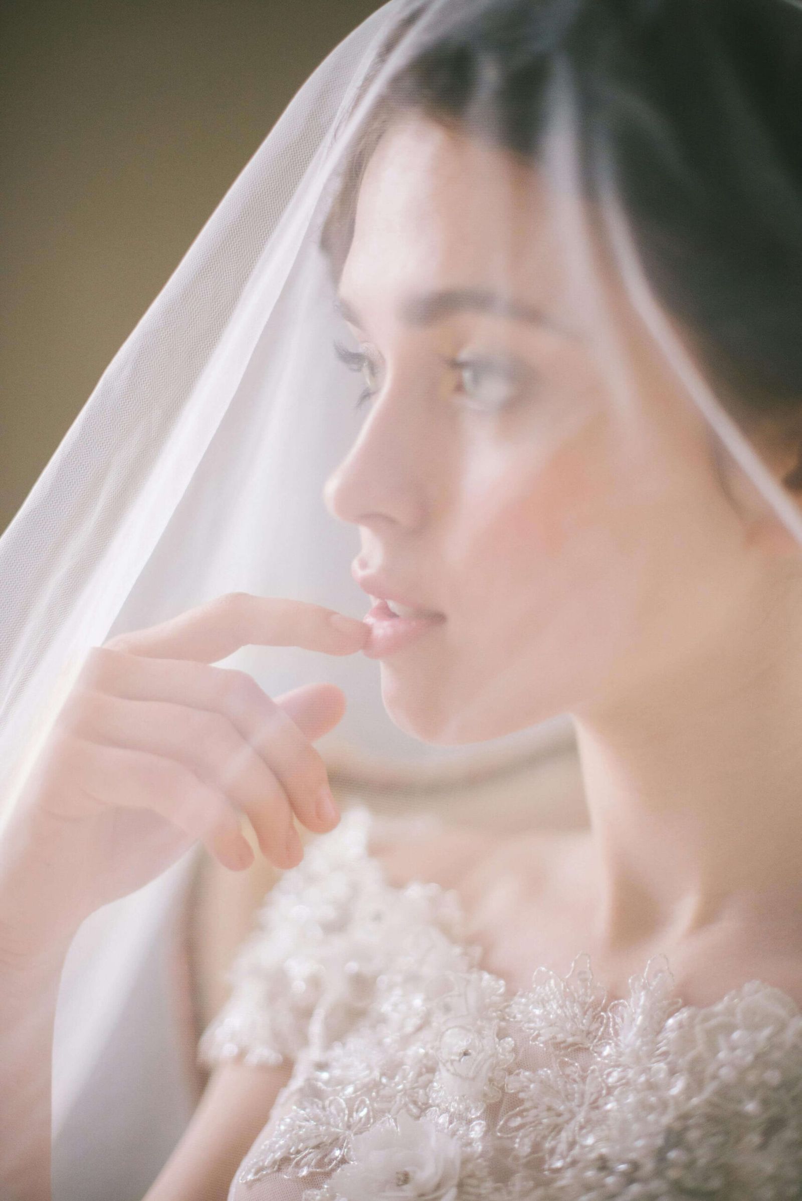 Close side portrait of a person beneath a sheer veil.