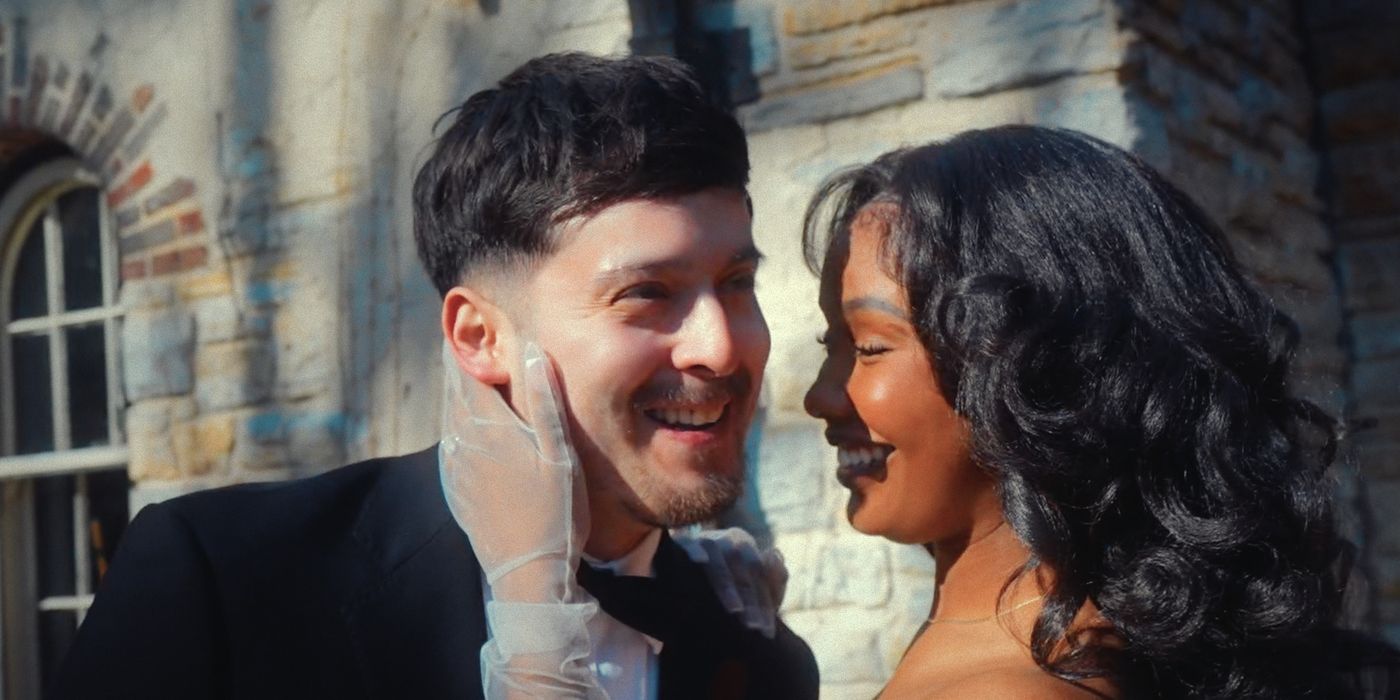 Close portrait of two formally dressed people facing closely beside a stone wall.