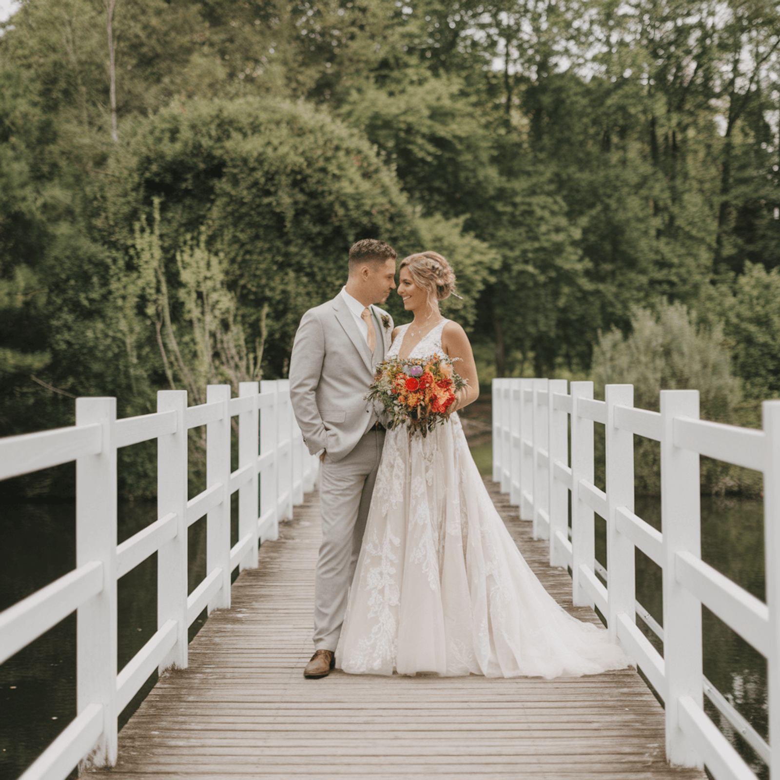 Couple in formal clothing embracing on a white footbridge.