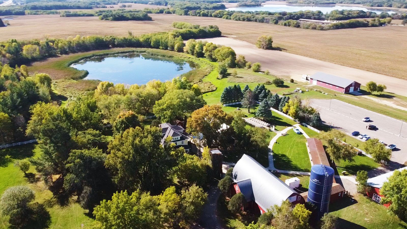 Farmstead Aerial Aerial view of buildings, trees, fields, and a small lake.