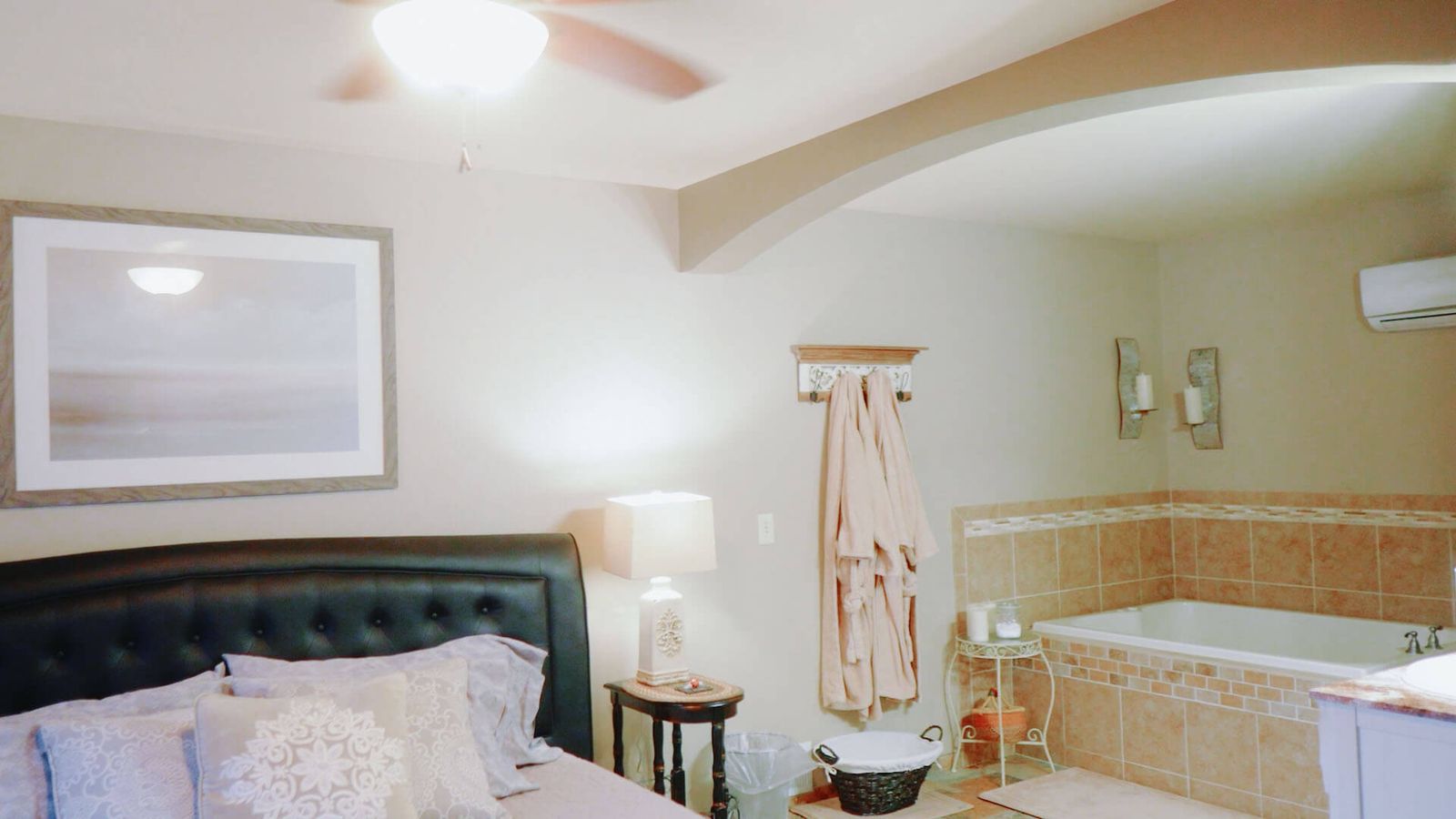 Bright bedroom with a bed, bench seating, and a tiled raised tub.