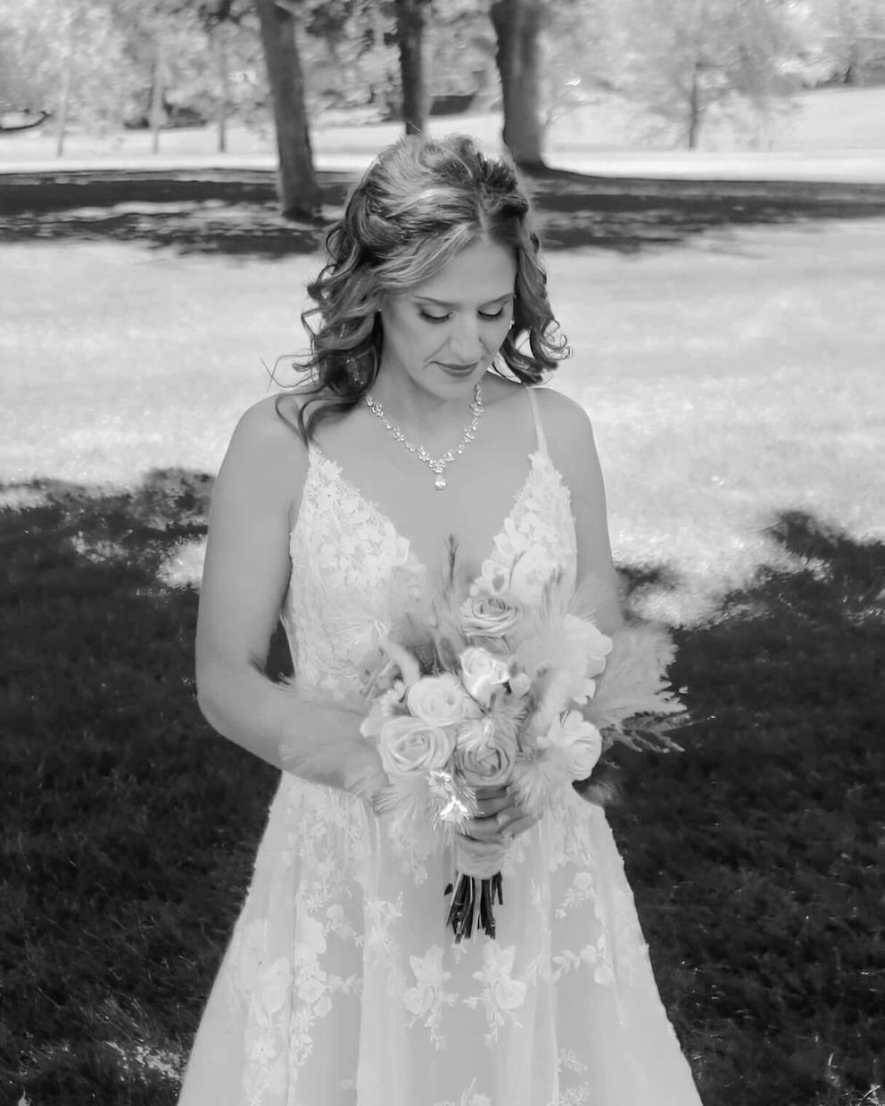 Bouquet Portrait Black-and-white portrait of a person in a white dress holding a bouquet outdoors.