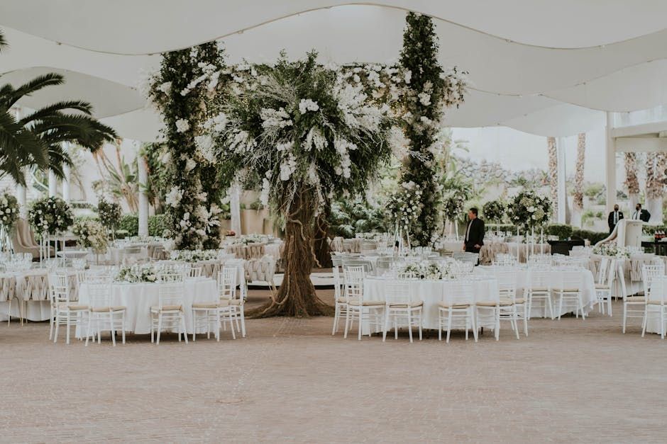 Tree Tent Reception White reception tent arranged with round tables beneath a large central tree.