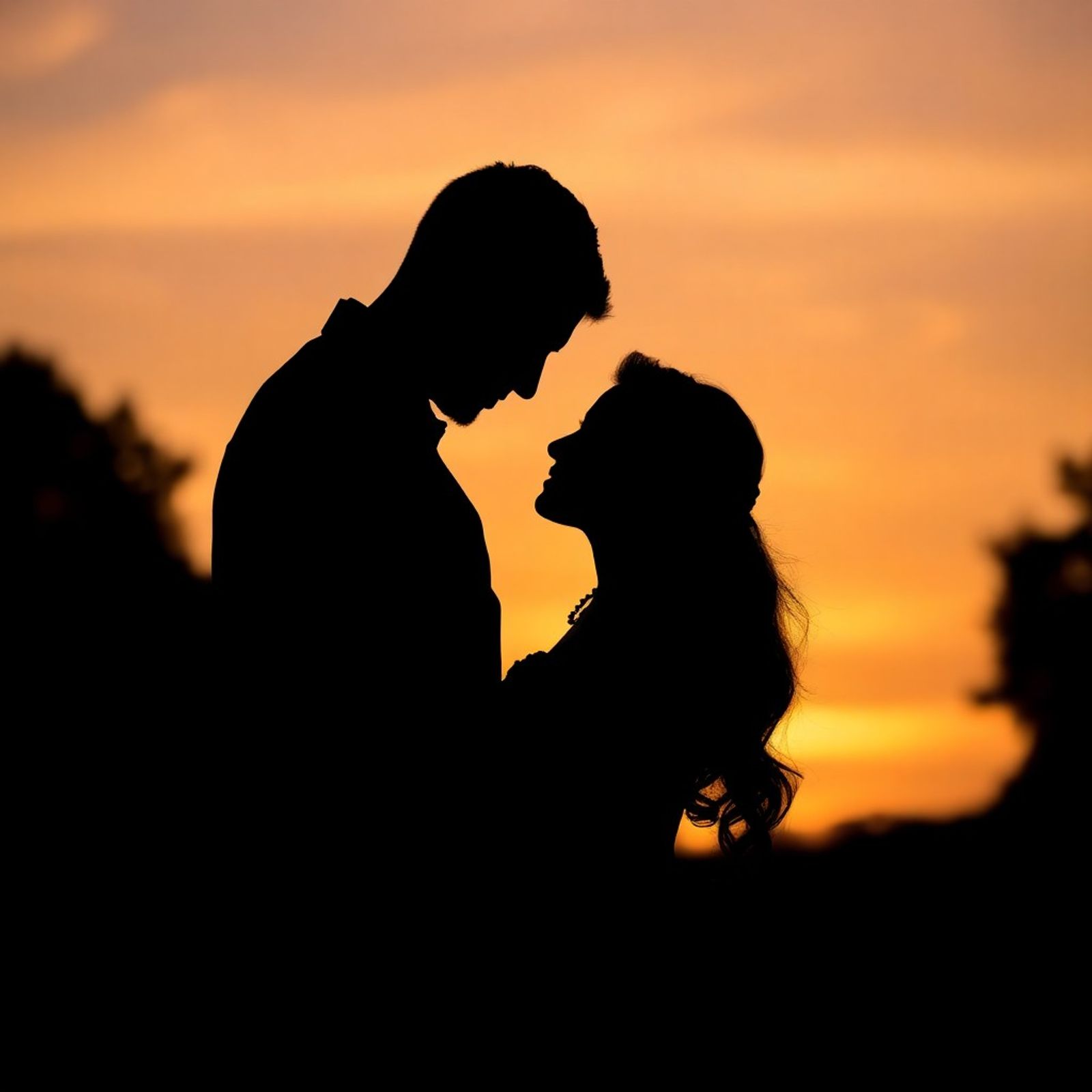 Silhouetted couple facing each other against an orange sunset.