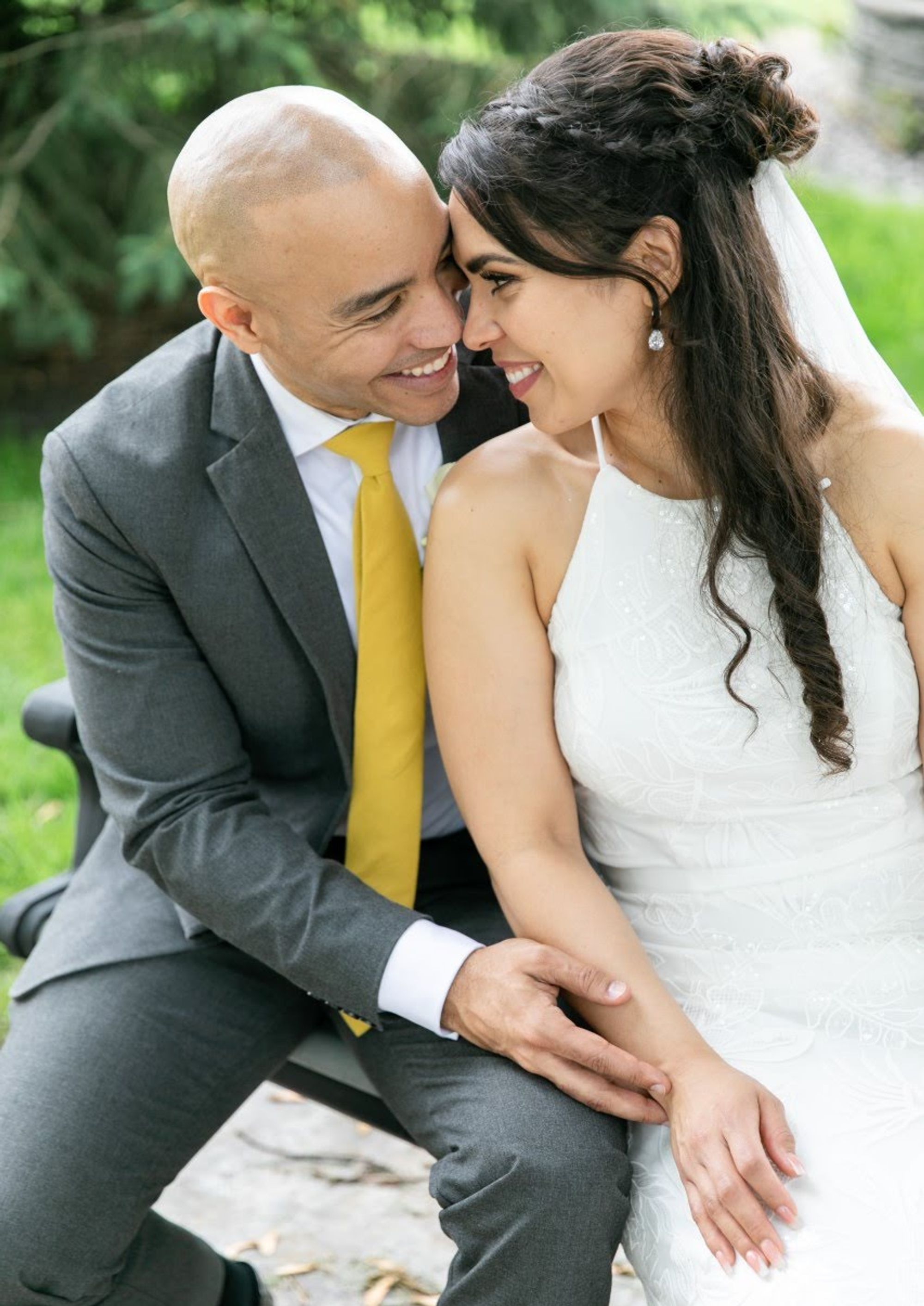 Two formally dressed people seated closely together outdoors.
