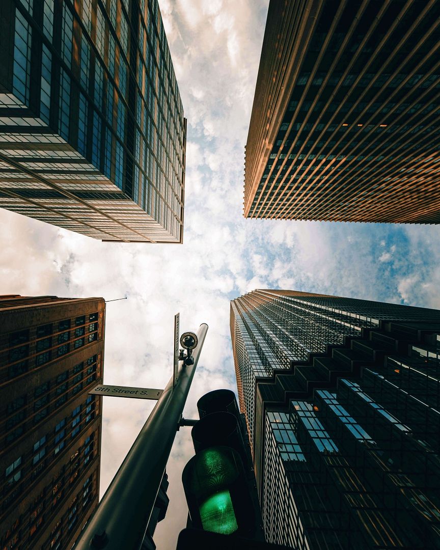 Upward City View Upward view between tall glass and stone buildings, with a person at the bottom.