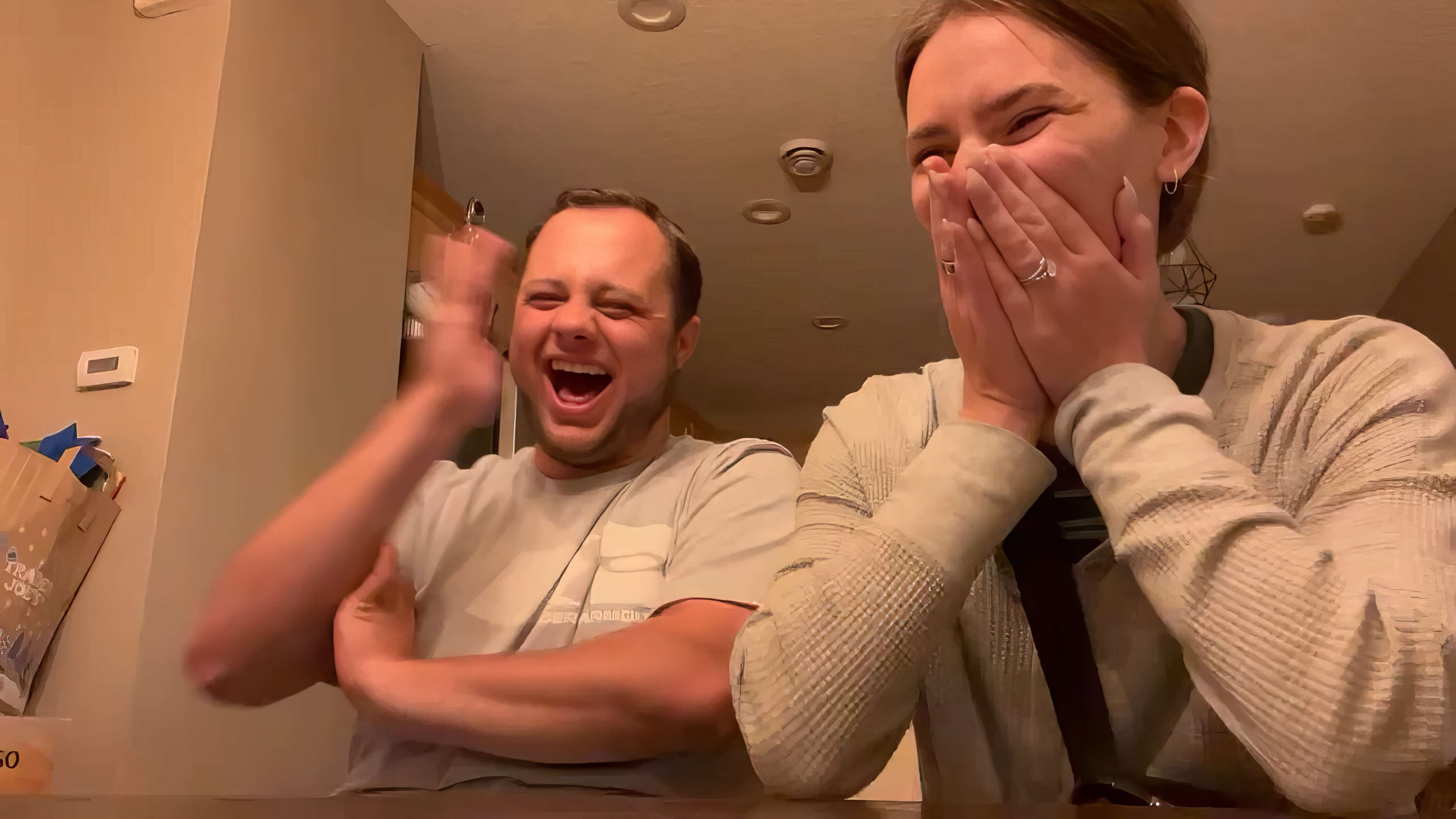 Couple laughing and reacting while viewing wedding film offscreen