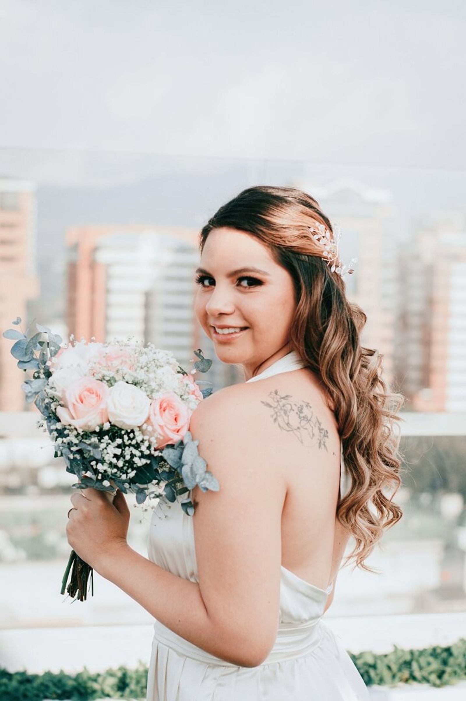 Person in a white wedding dress holding a bouquet and looking toward the camera.