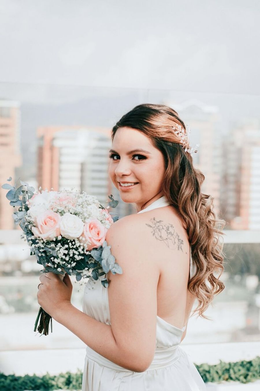 Person in a white wedding dress holding a bouquet and looking toward the camera.