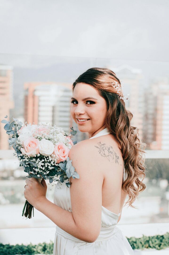 Bouquet Portrait Person in a white wedding dress holding a bouquet and looking toward the camera.