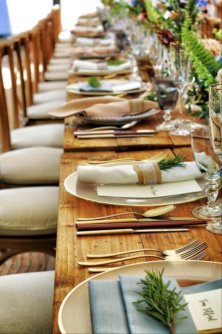 Rustic Banquet Table Long rustic banquet table set with plates, napkins, and greenery.