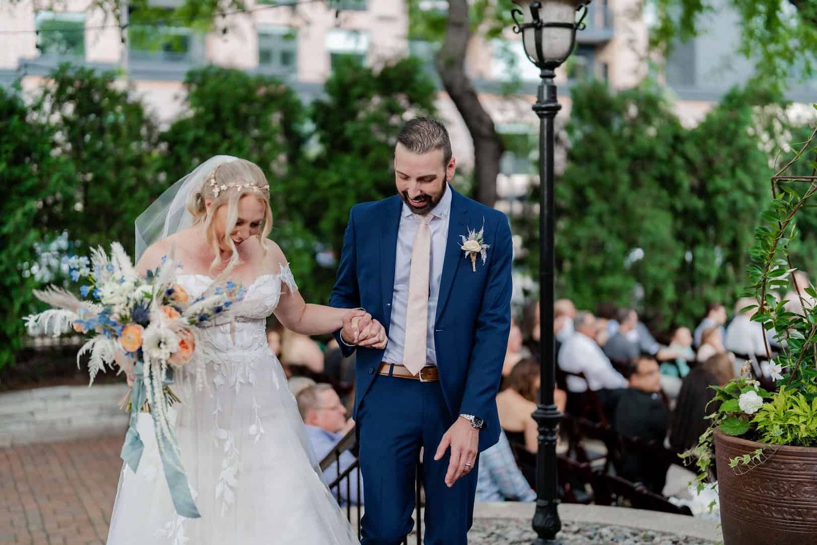 Outdoor Ceremony Walk Person in a white wedding dress walking beside a person in a blue suit during an outdoor ceremony.
