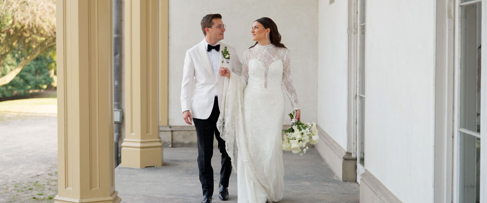 Columned Corridor Two people in white formal clothing walking through a pale columned corridor.