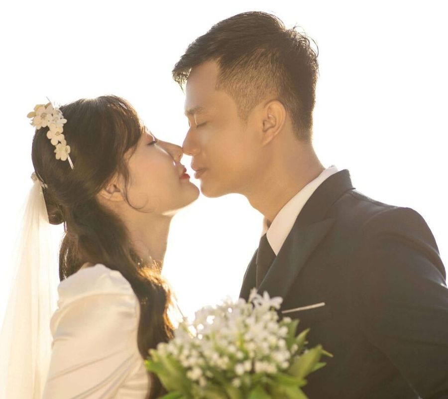 Backlit Couple Backlit couple in wedding attire touching foreheads while one holds a bouquet.
