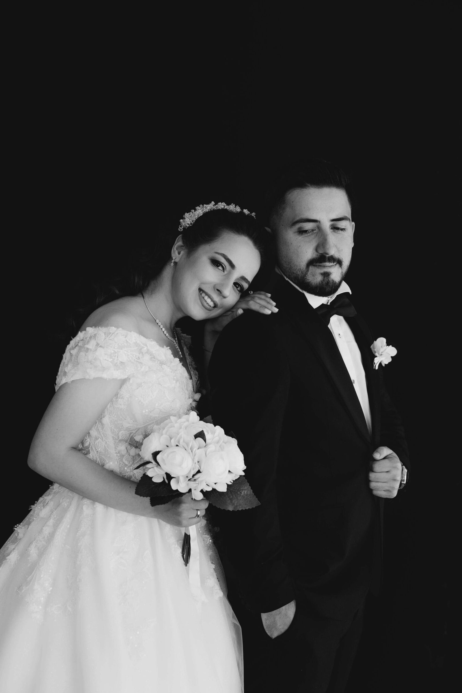 Black and White Portrait Black-and-white portrait of a couple in wedding attire standing together against a dark background.