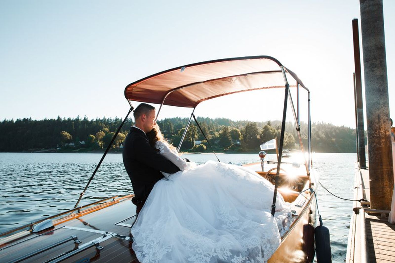 Couple in wedding attire seated together on a small boat.