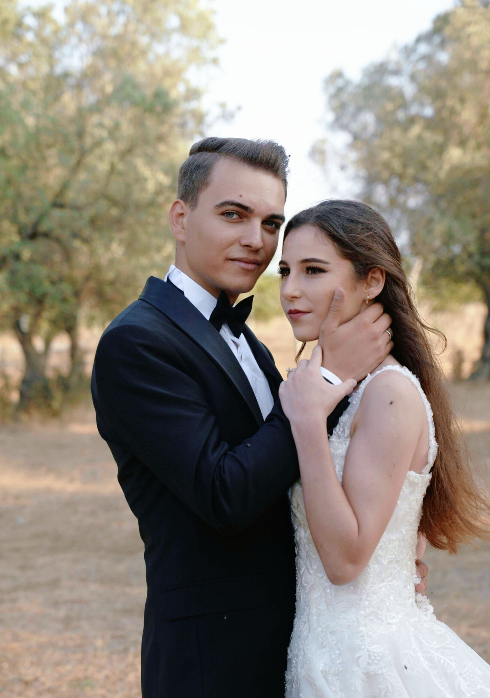 Woodland Portrait Couple in wedding attire posing outdoors among trees.