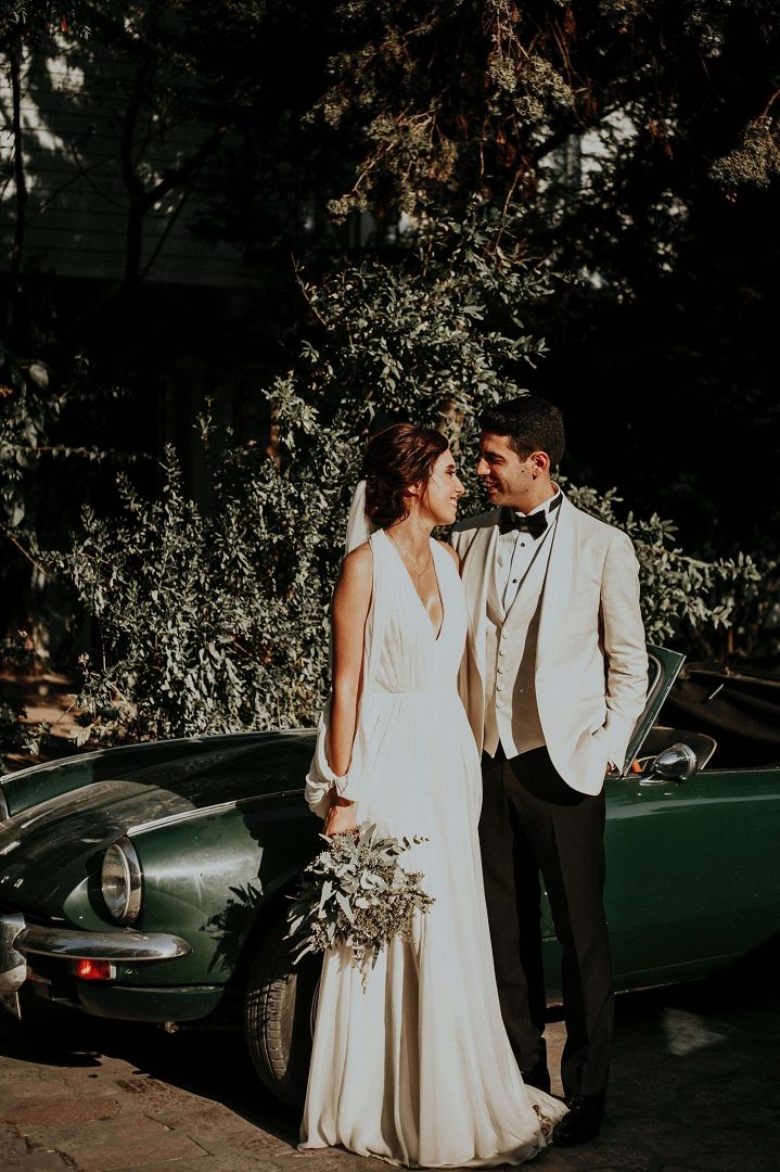 Night Car Portrait Couple in wedding attire standing beside a dark green vintage car at night.
