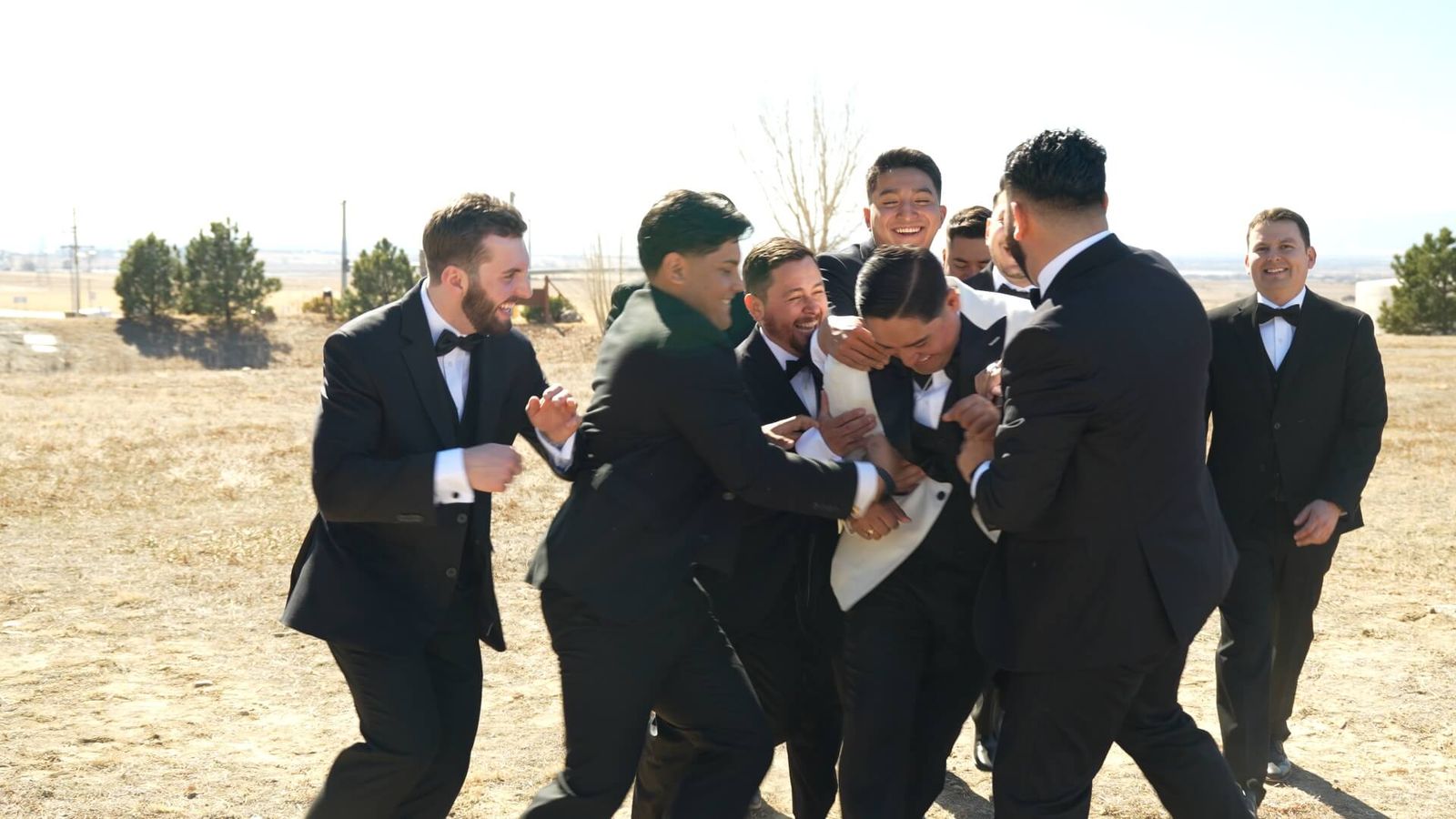 Several men in dark suits gather around one man outdoors